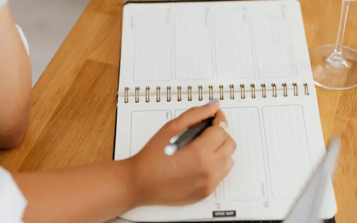 Personne organisant ses notes dans un carnet près d’un ordinateur