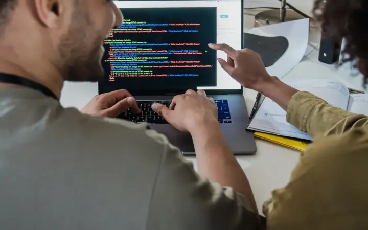Deux développeurs relisant ensemble du code affiché sur un ordinateur portable