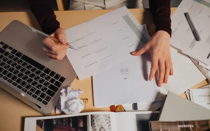 Personne sélectionnant et annotant des documents autour d’un ordinateur portable