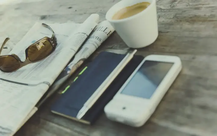 Smartphone posé près d’un journal et d’une tasse de café